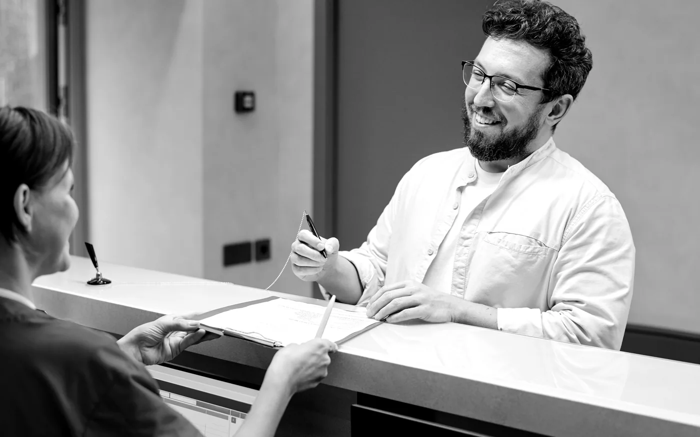 Black-and-white clinical consultation at a front desk