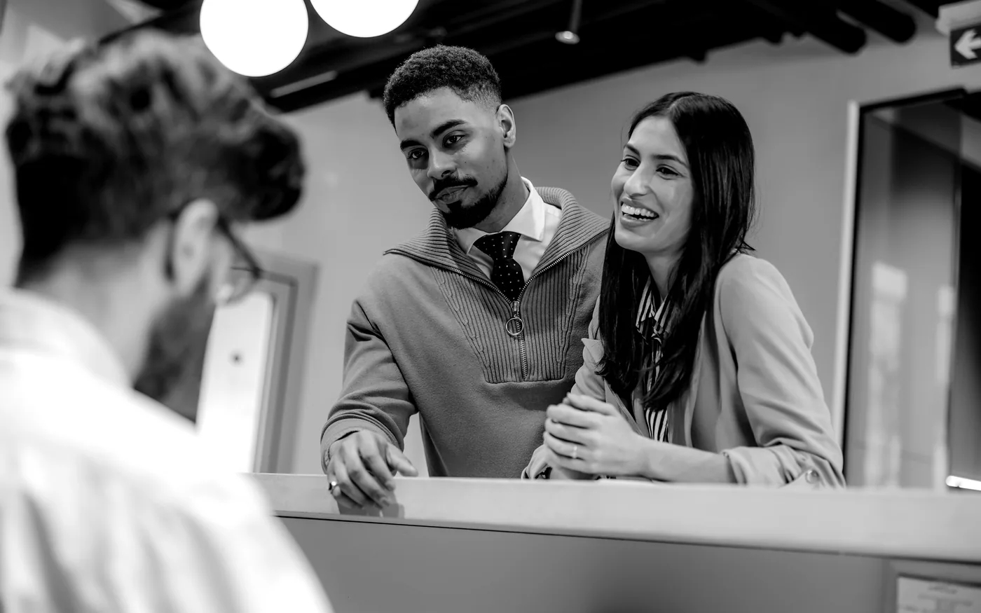Black-and-white front desk team helping a dental practice visitor